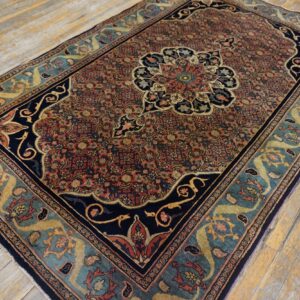 Ornate medallion rug featuring red, navy, and teal colors on worn, light wood planks.