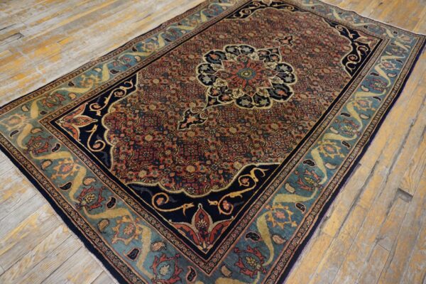 Ornate medallion rug featuring red, navy, and teal colors on worn, light wood planks.