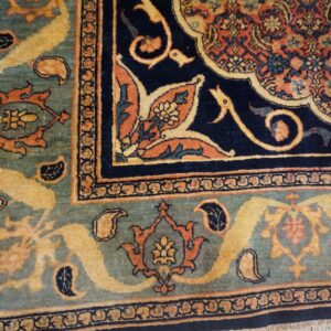 Detailed rug corner displaying teal, navy, orange, and gold traditional floral and paisley patterns.