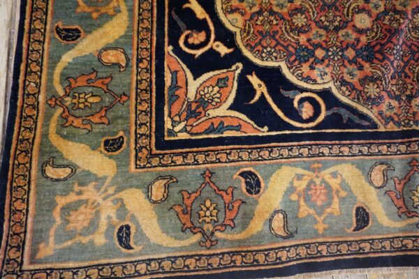 Detailed rug corner displaying teal, navy, orange, and gold traditional floral and paisley patterns.