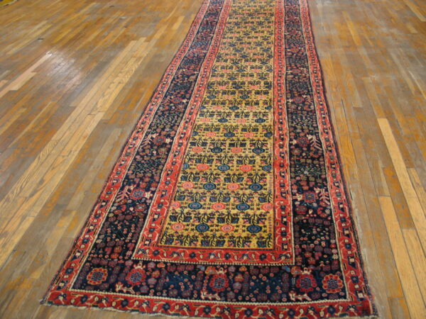 Traditional runner featuring a dense navy border and a central yellow field sits on hardwood flooring.