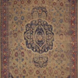 Distressed traditional rug featuring a large navy medallion and red floral border on a faded tan field.