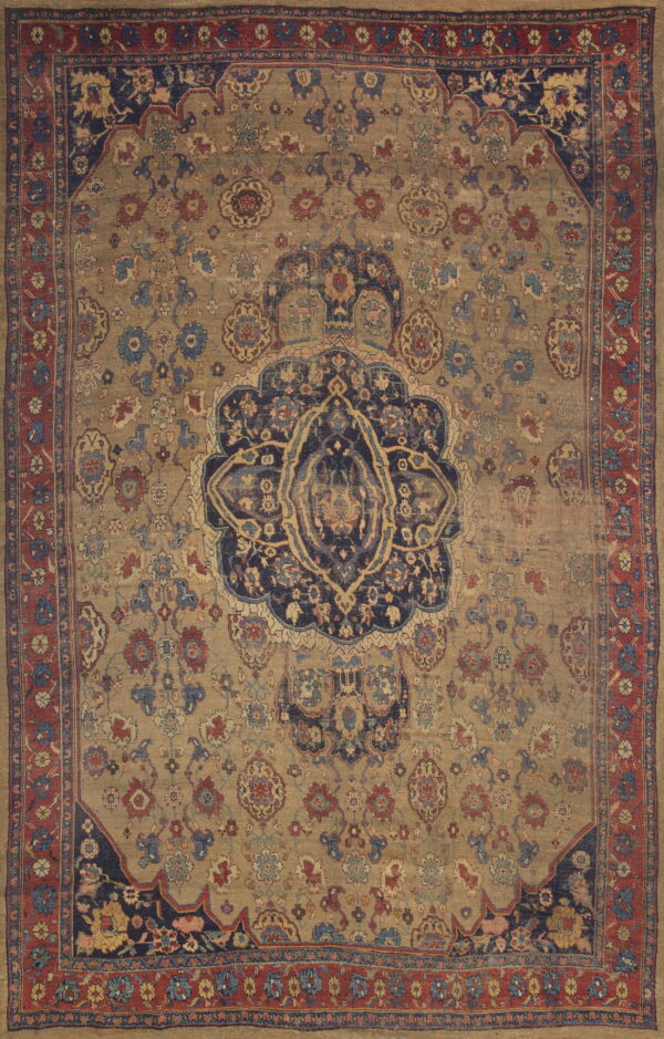 Distressed traditional rug featuring a large navy medallion and red floral border on a faded tan field.