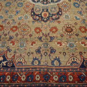 Muted beige rug with detailed curvilinear floral patterns in navy, red, and light blue.