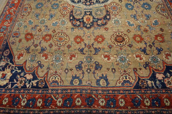 Muted beige rug with detailed curvilinear floral patterns in navy, red, and light blue.