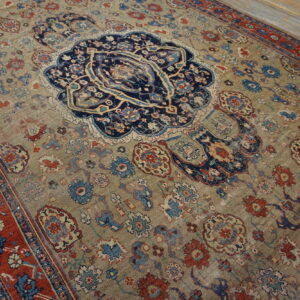 Low-pile ornate rug featuring a central navy medallion, gold field, and deep red borders on wood floors.