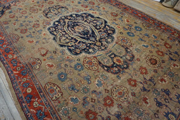 Low-pile ornate rug featuring a central navy medallion, gold field, and deep red borders on wood floors.