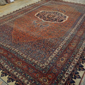 Rust and navy blue traditional rug with a central medallion resting on rustic wood planks.