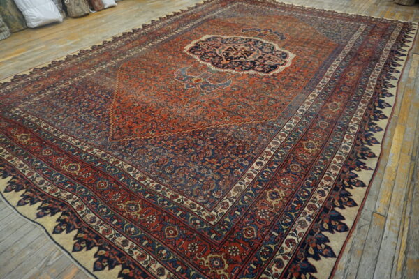 Rust and navy blue traditional rug with a central medallion resting on rustic wood planks.