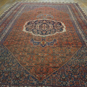 Rust and navy blue medallion rug with intricate patterns displayed on rustic hardwood floor.
