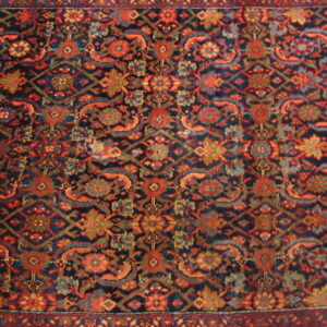 Traditional rug pattern in deep navy and vibrant rust red with detailed floral and geometric motifs.