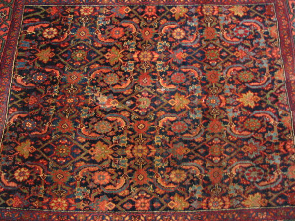 Traditional rug pattern in deep navy and vibrant rust red with detailed floral and geometric motifs.