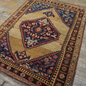 Low-pile rug featuring a navy geometric medallion on a brown field, displayed on distressed wood planks.