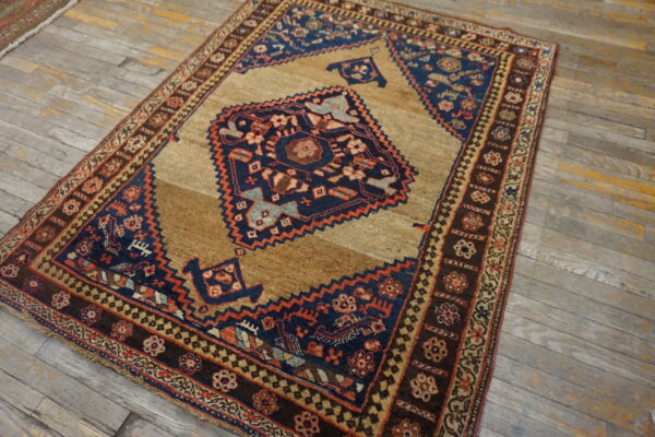 Low-pile rug featuring a navy geometric medallion on a brown field, displayed on distressed wood planks.