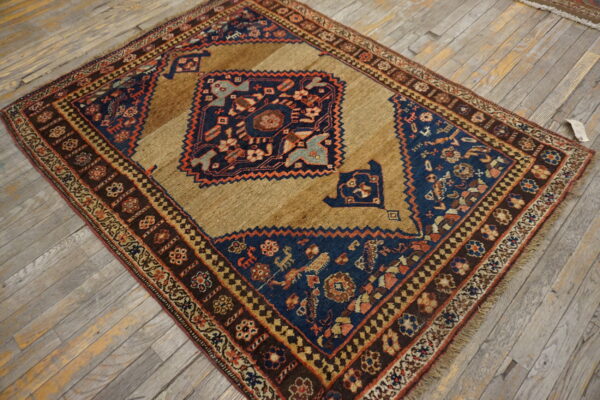 Geometric brown, navy, and rust-colored rug with a central design resting on distressed wood flooring.