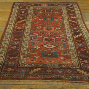 Geometric red and brown runner rug with blue accents lies on yellow wide-plank wood flooring.