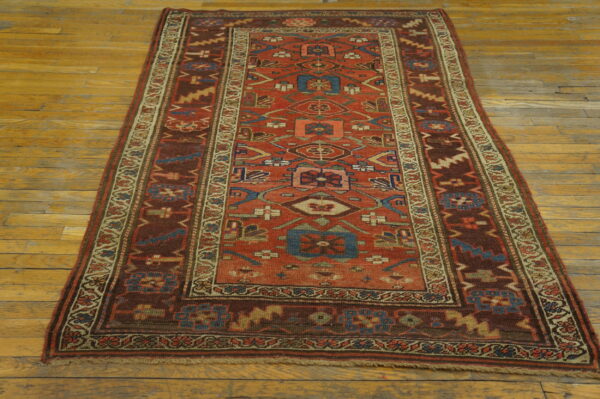Geometric red and brown runner rug with blue accents lies on yellow wide-plank wood flooring.