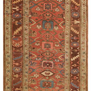 Rust field rug with geometric tribal designs in deep brown, blue, beige, and olive green.