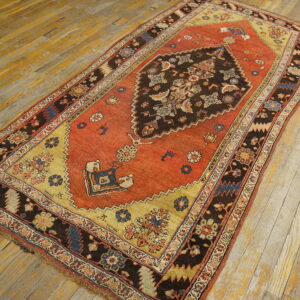 Traditional rust and dark brown medallion rug featuring gold spandrels rests on worn wood flooring.