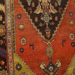 Low-pile rug featuring a rust red field, dark brown stepped medallion, and intricate geometric and floral borders.