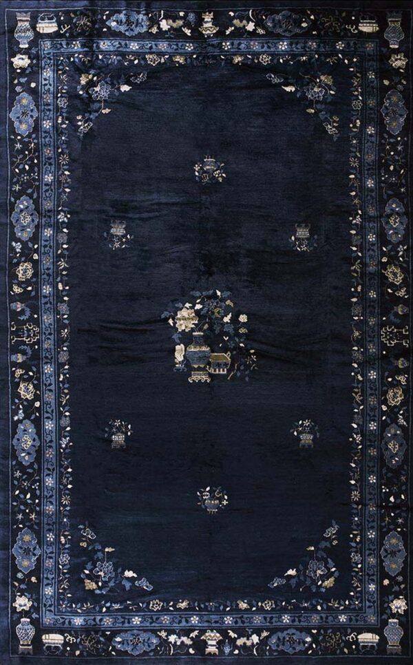 Plush navy area rug with symmetrical patterns of flowers and vases in light blue, gold, and cream.