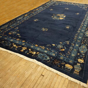 Navy area rug featuring floral and vase motifs in gold and teal, laid on plank wood flooring.