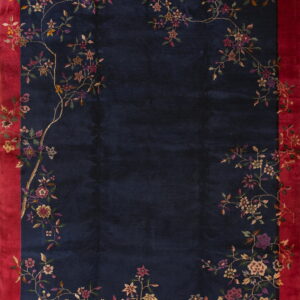 Navy blue rug featuring a vibrant red border and delicate multicolored floral patterns spanning the edges.