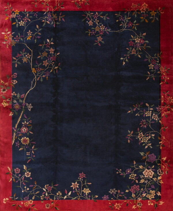Navy blue rug featuring a vibrant red border and delicate multicolored floral patterns spanning the edges.