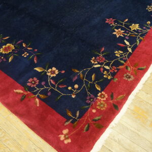 Navy rug featuring colorful floral patterns bordering the deep red frame on distressed wood floors.