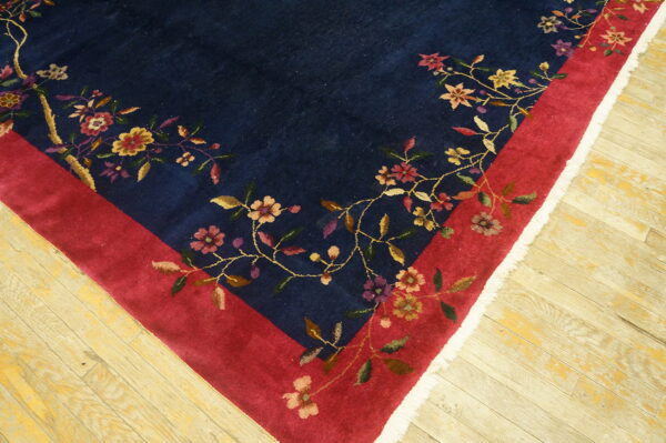 Navy rug featuring colorful floral patterns bordering the deep red frame on distressed wood floors.