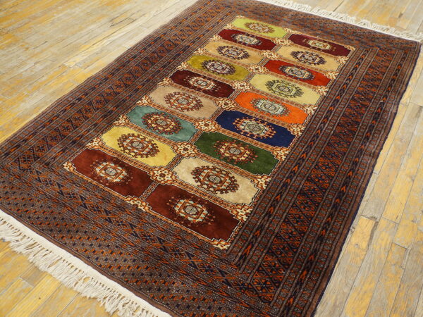 Traditional rug with multi-colored rectangular panels and dark geometric borders on a distressed wood floor.