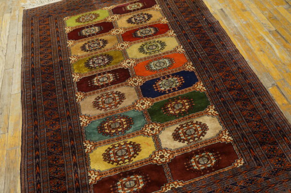 Multicolor block rug with central medallions and a patterned border rests on distressed wood flooring.