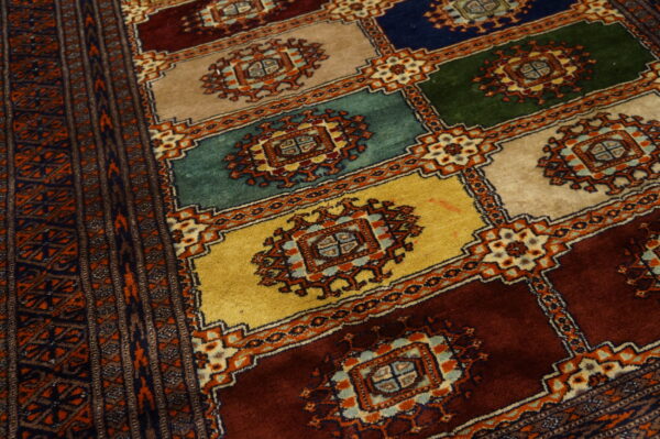 High-pile rug featuring a geometric block pattern in gold, teal, deep red, navy, and tan.