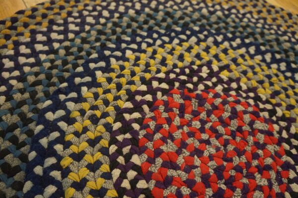 Braided rug featuring thick rings of multicolored coils in red, yellow, blue, purple, and gray.