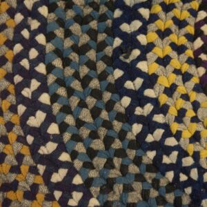 Thick braided rug with colorful sections of blue, gray, yellow, red, and white resting on wood floor.