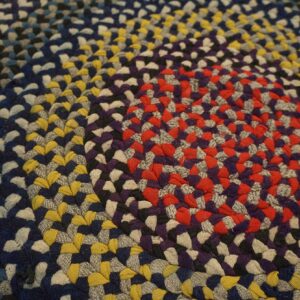 Multicolor braided rug with a radial pattern of red, purple, blue, and yellow segments.