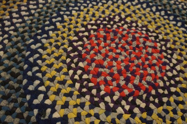 Multicolor braided rug with a radial pattern of red, purple, blue, and yellow segments.