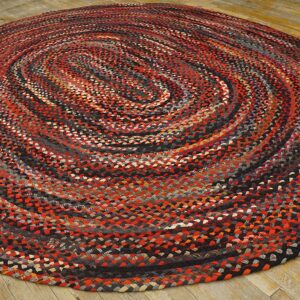 Multicolor braided round rug with red and black tones on light, distressed wood flooring.