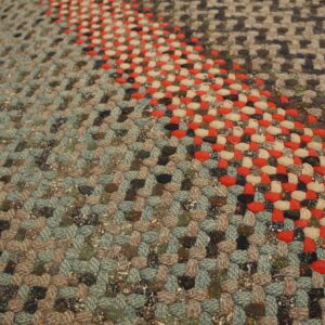 Chunky braided rug showing diagonal stripes in mixed muted teal, brown, red, and cream tones.