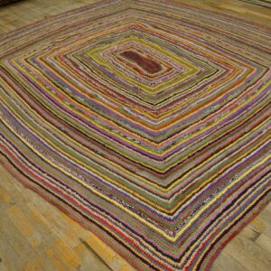 Multicolored braided rag rug features a diamond pattern on light brown hardwood planks.
