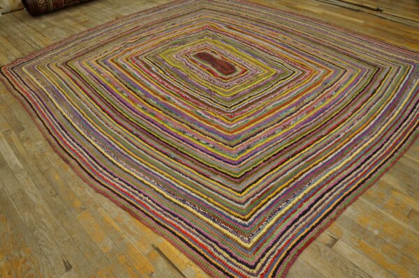 Multicolored braided rag rug features a diamond pattern on light brown hardwood planks.