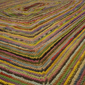 Multicolored braided rag rug showing tight texture and a repeating square geometric pattern.