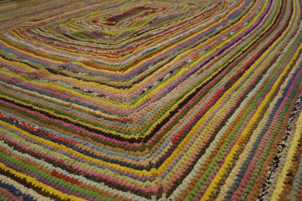Multicolored braided rag rug showing tight texture and a repeating square geometric pattern.