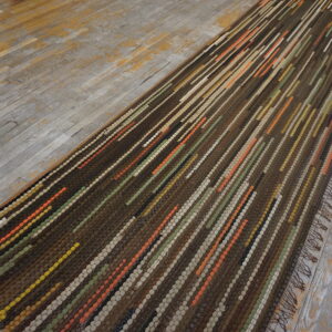 Textured brown runner with orange, green, and cream diagonal lines covers rustic wood flooring.