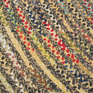 Diagonal rows of multicolor textured rug in beige, black, red, and blue resting on a wood floor.