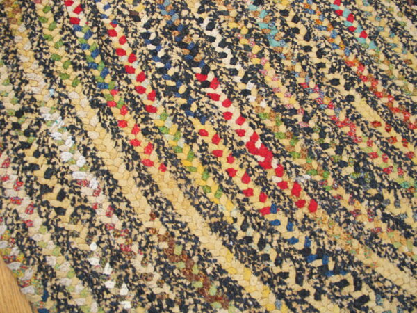 Diagonal rows of multicolor textured rug in beige, black, red, and blue resting on a wood floor.