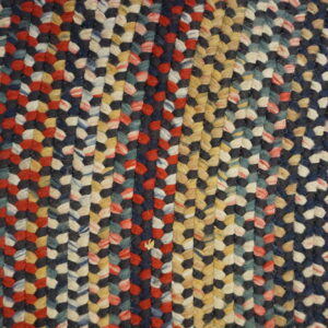 Braided rug in mixed navy, red, cream, yellow, and teal colors shown on wood flooring.