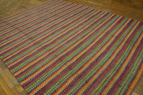 Vibrant multi-color flat-weave rug with diagonal stripes is displayed on rustic hardwood flooring.