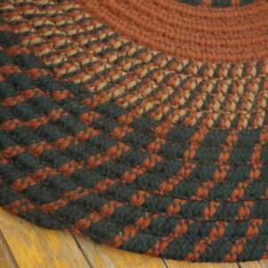 Close-up of a circular braided rug in concentric rings of rust, dark green, and tan over yellow wood floors.