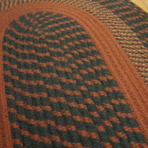 Close-up of a braided rug showing rust and dark green striped bands on light wood floor.